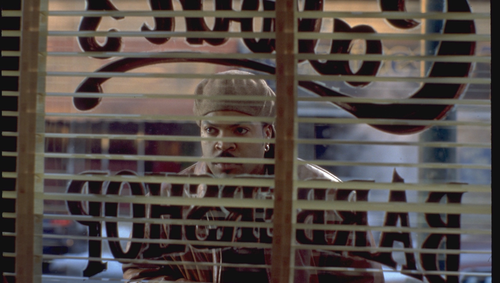 A man looks through the window of a barbershop from outside on the street