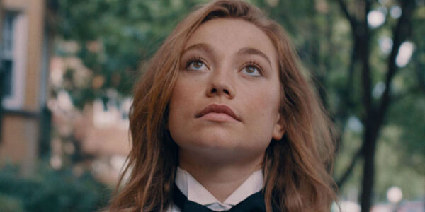 A girl with long red hair and wearing a tuxedo looks up
