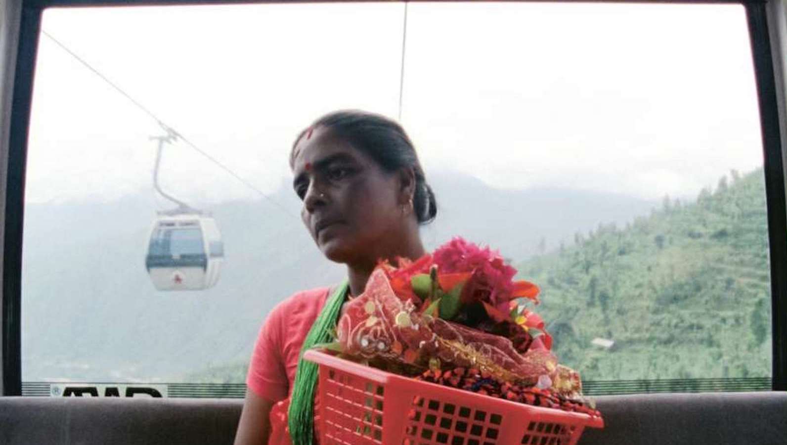manakamana A woman carries a red basket full of flowers in a gondola high in the mountains