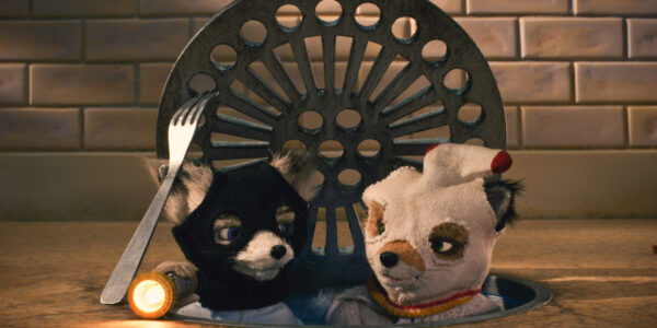 Two stop motion foxes with socks on their heads pop their heads out of a sewer manhole cover