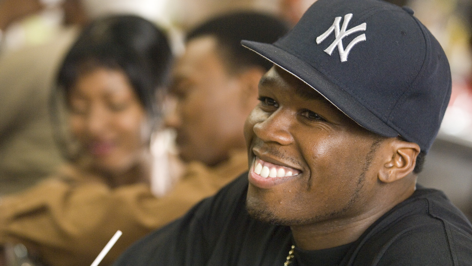 A close-up of a smiling man in a New York Yankees baseball cap