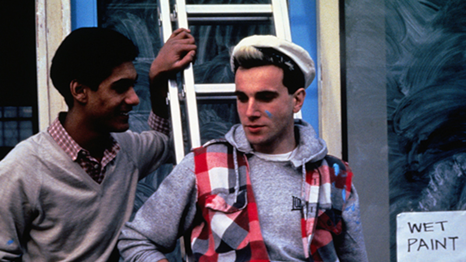 Laundrette Two men stand by a ladder outside a shop, one in a white hat with paint smudge on his face