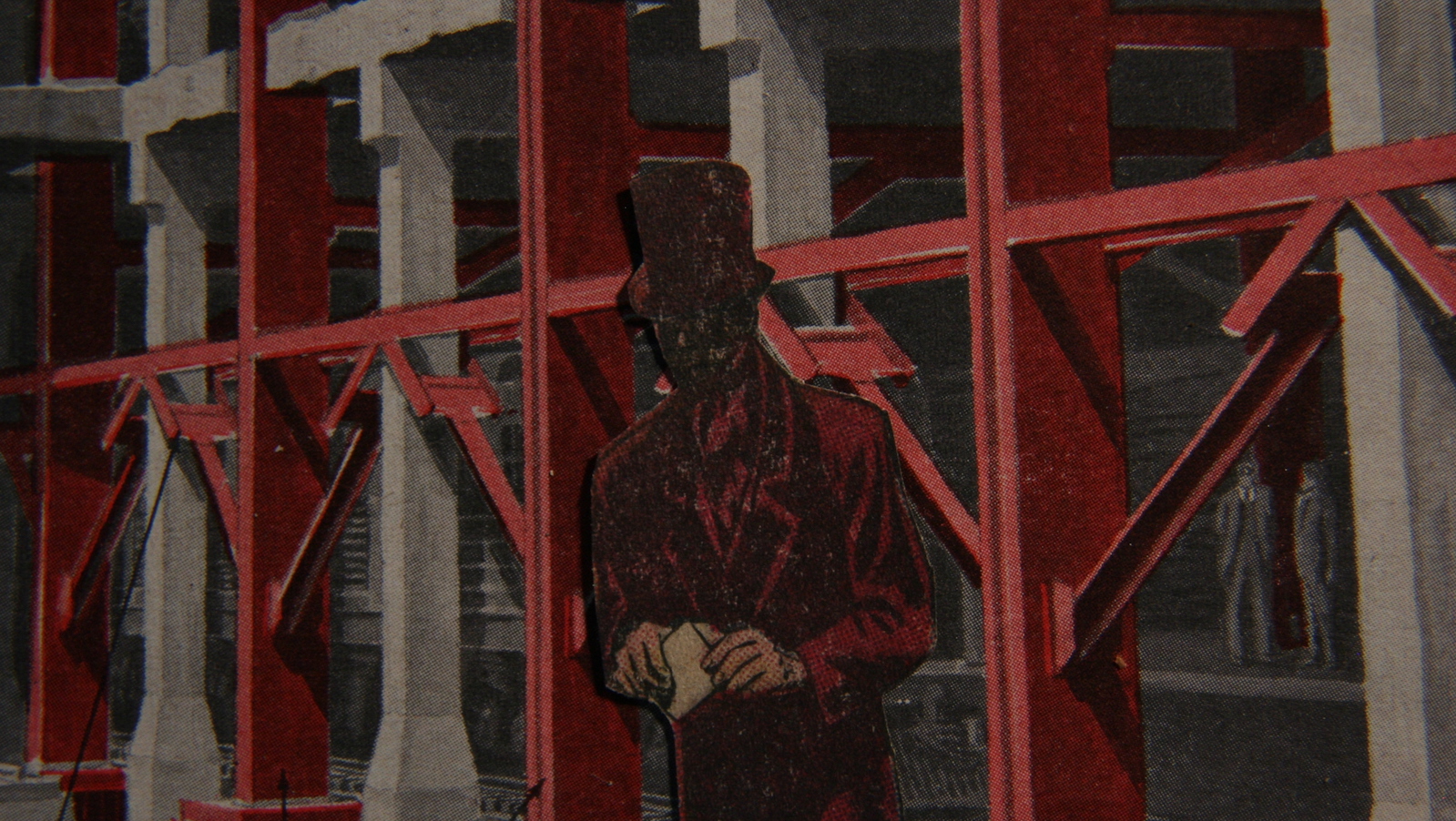 A cutout of a man in a red top hat and a dark face standing against red scaffolding