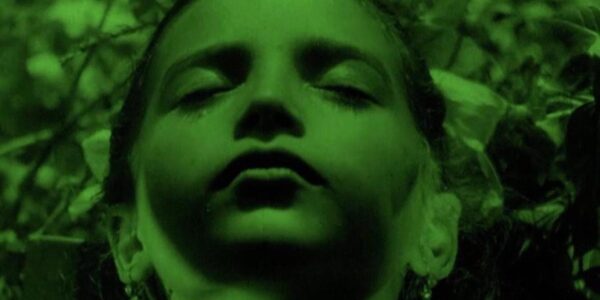 An image with a green filter of a young girl's face in extreme closeup, eyes closed,.