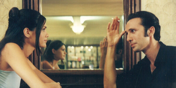 A man and woman sit in a cafe facing each other in front of a mirror