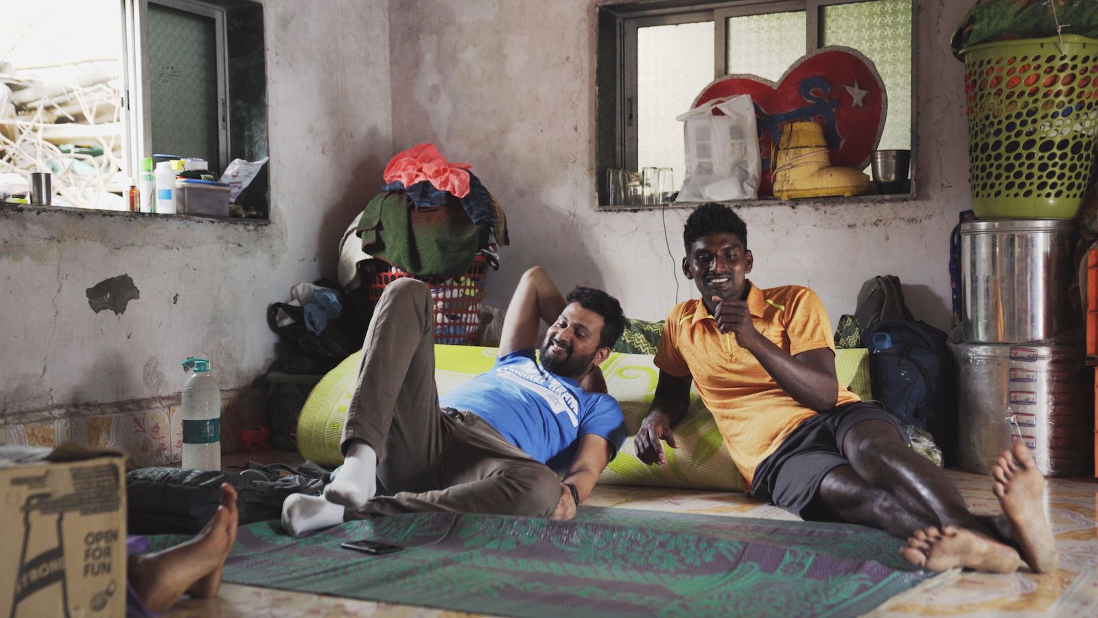Two men smile and sit on the floor, relaxing