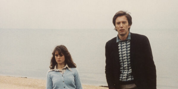 A man and woman walk on a beach