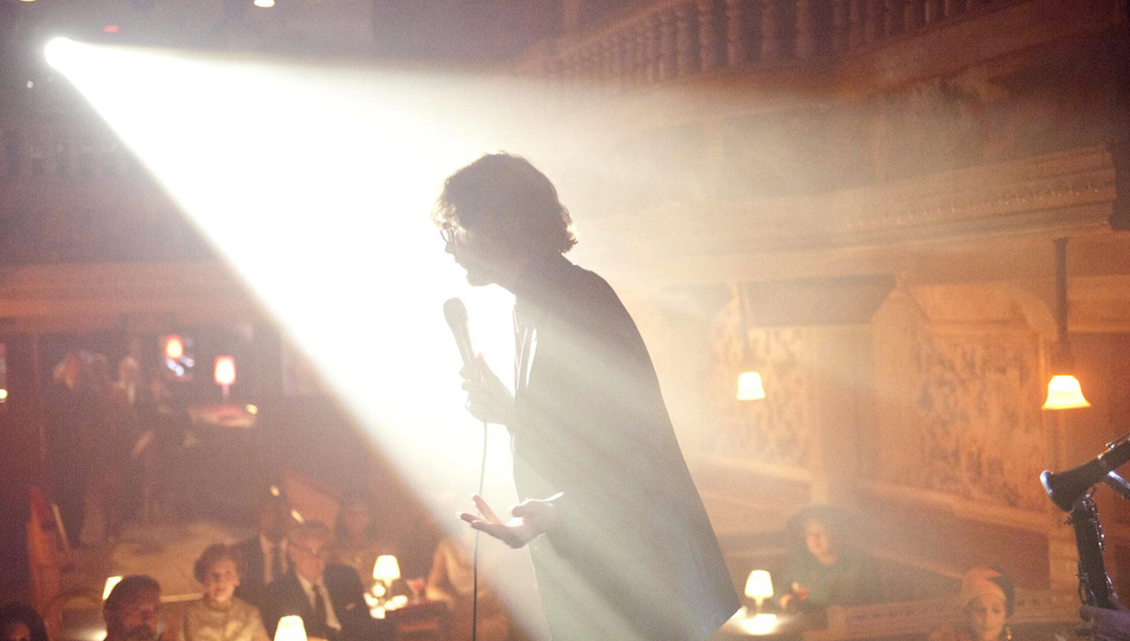 A silhouette of a man in a nightclub holding a microphone