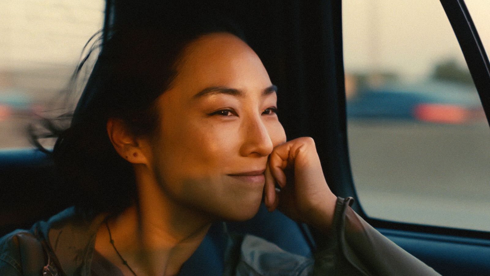 A woman smiles in the back of a car