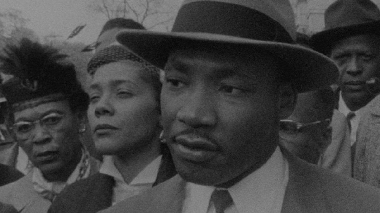 Martin Luther King Jr stands in a crowd wearing a fedora