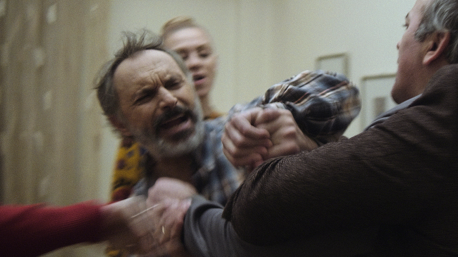 Dignity A white-bearded man struggling with another man during a fight inside a house