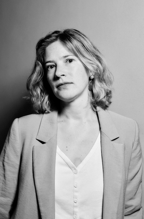 A studio portrait of a person wearing a gray suit