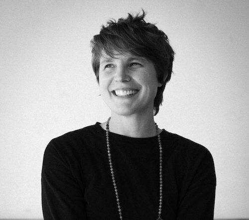 A woman smiling wearing a long necklace