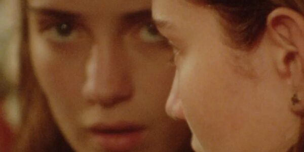An extreme closeup of a woman looking in a mirror and the camera with a blank expression
