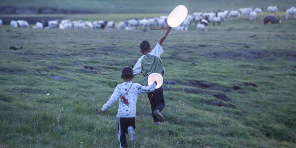 Two children running with balloons in a field