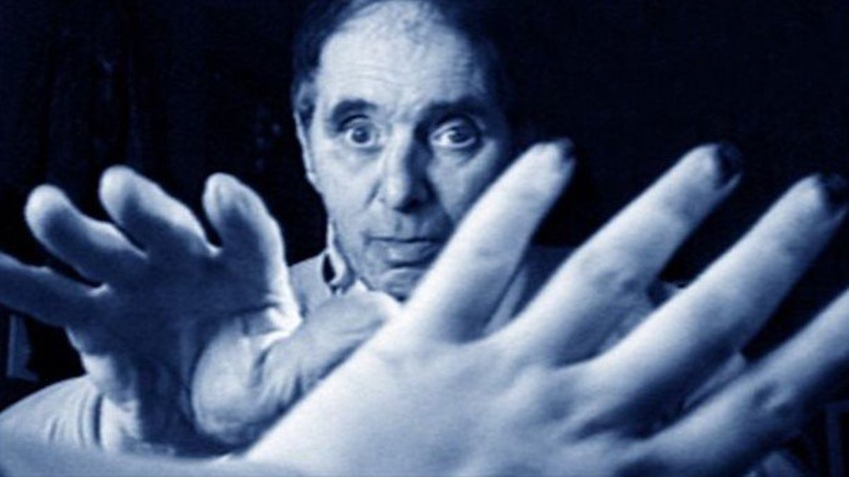 A man reaches his hand to another hand, which is huge in the foreground.