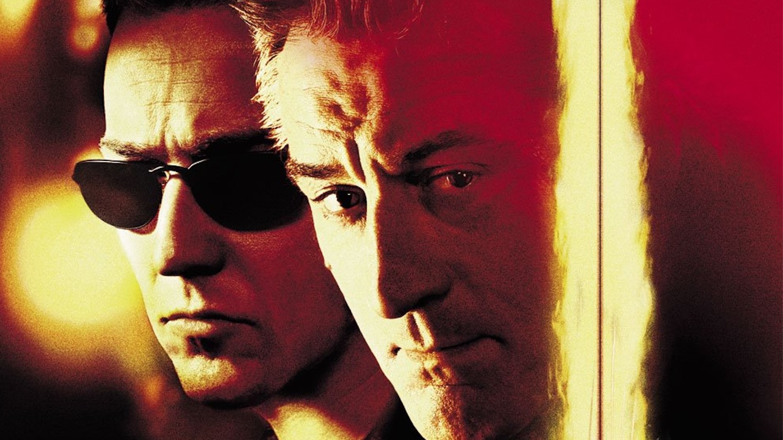 Two men, one wearing sunglasses, look to the left against a reddish yellow haze