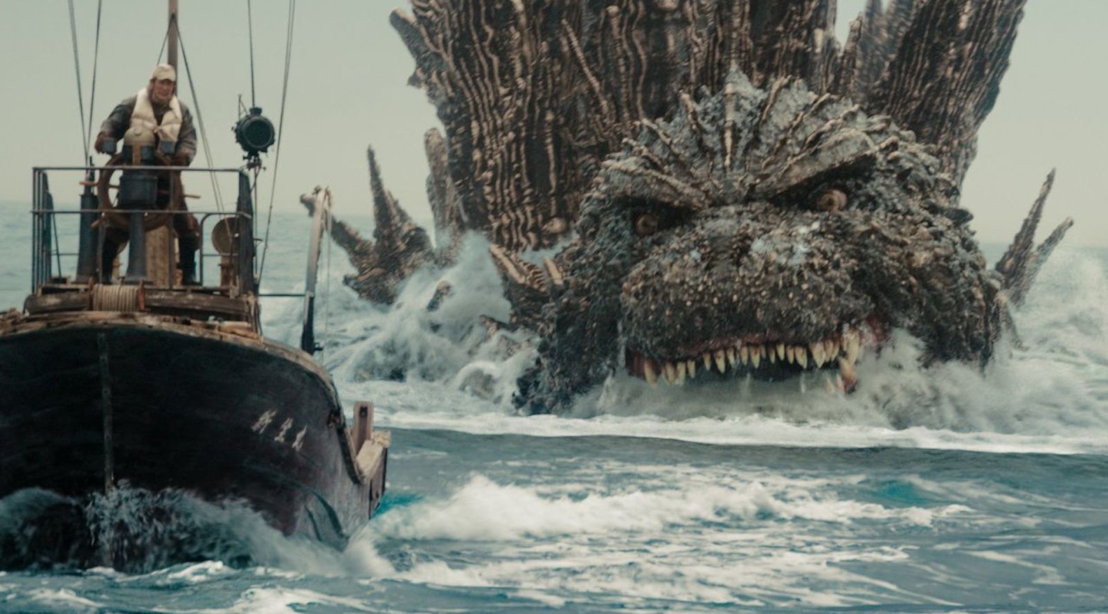 A gigantic beast with sharp teeth rises out of the water, threatening a fisherman in a small boat with Japanese writing on the side.