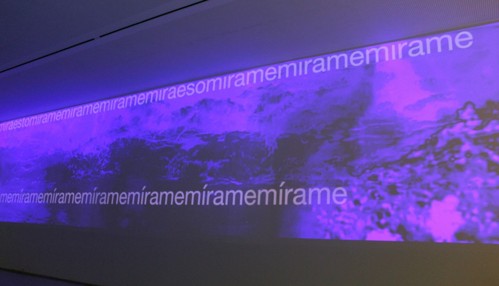A purple screen at a Museum showing an installation with text scrolling across it.