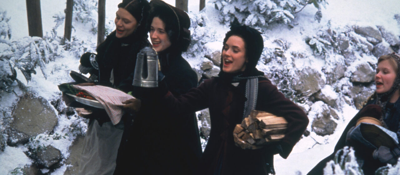 Four young women sing merrily in the snow and carry plates covered with napkins, a pot of coffee, and piles of wood.