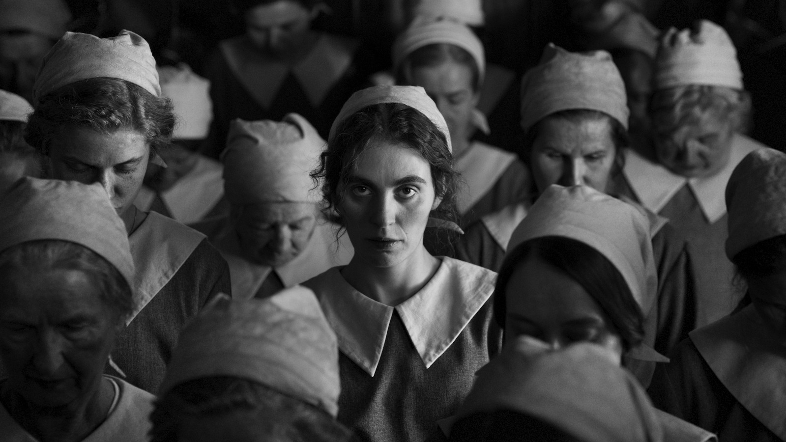 Girl with Needle A young woman in a white Dutch-style maid hat and uniform stands in a crowd and looks up while all the women around her look down.