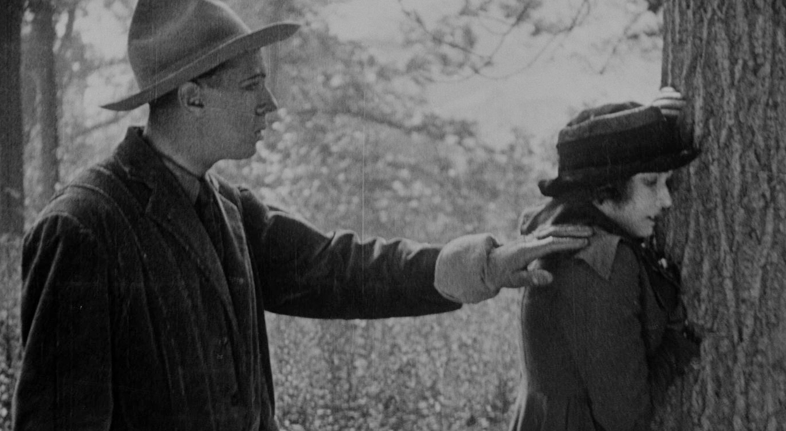 A man in a cowboy hat tenderly places a gloved hand on a woman's shoulder.