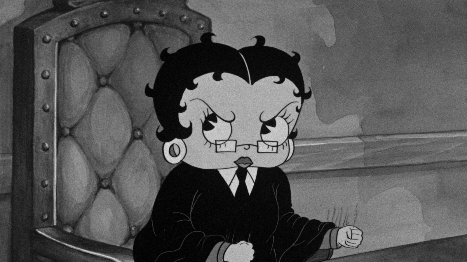 Black-and-white image of the cartoon character Betty Boop wearing glasses, a black robe and tie, and a serious expression as she sits in a judge's chair.