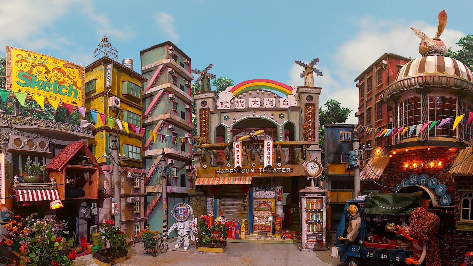 A vibrant cityscape in many colors, with the words HAPPY SUN THEATER above the center building.