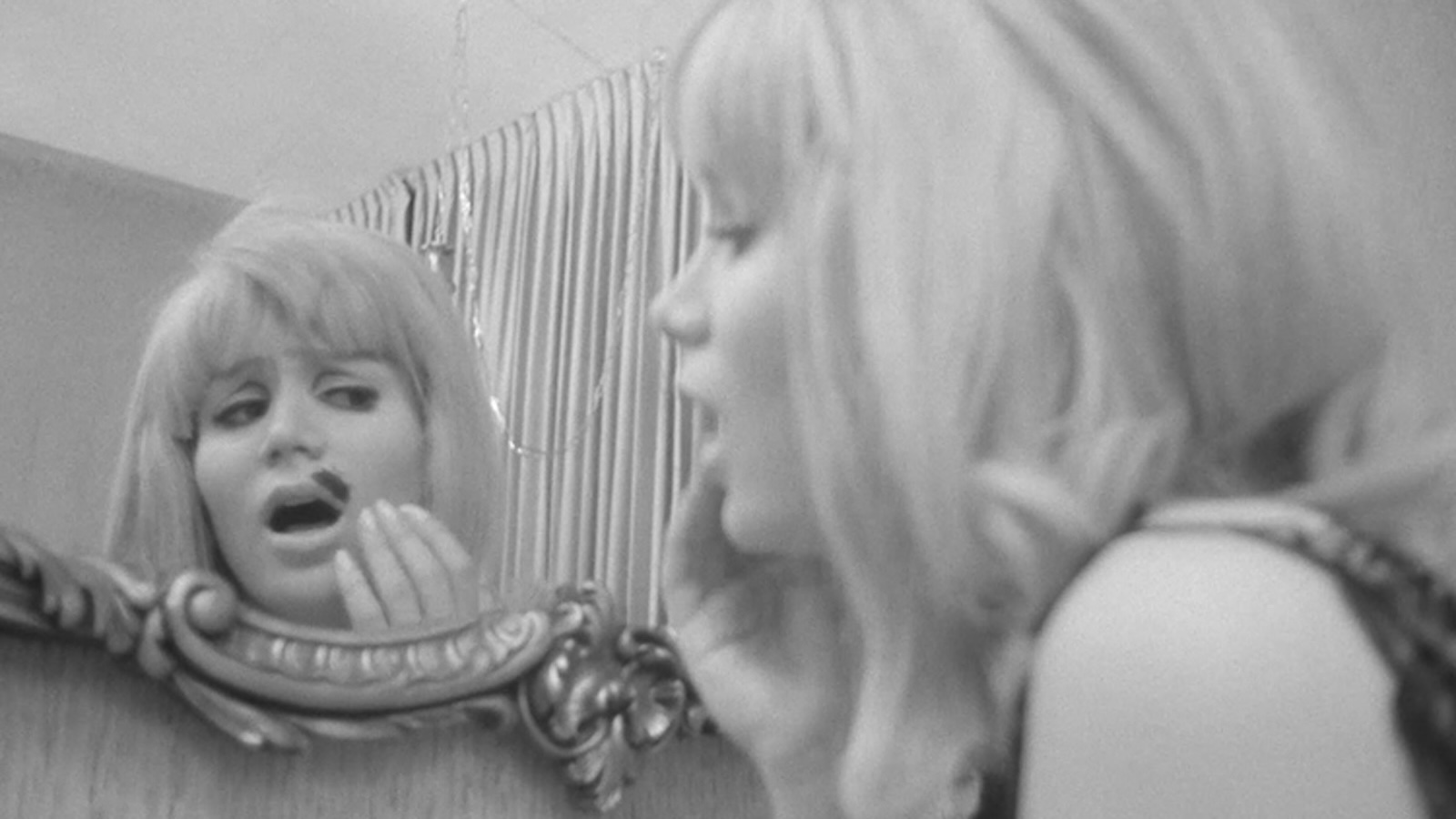 IndecentDesires3 A blonde woman looks in a mirror, aghast by a black blotch on top of her lip.