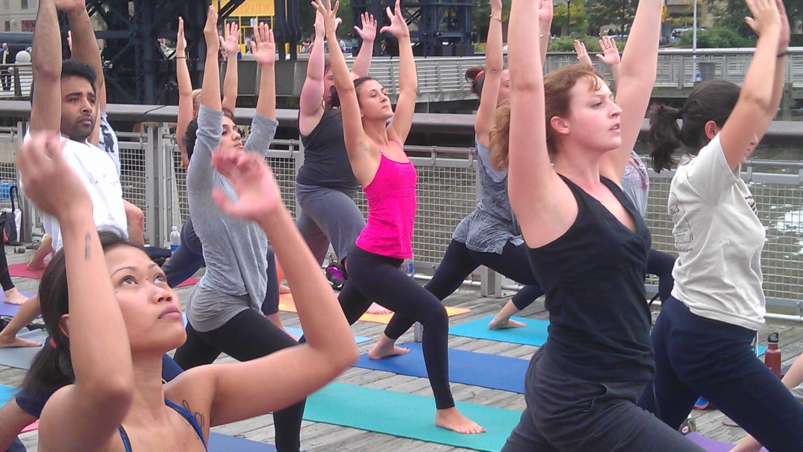 Yoga in the courtyard Women standing outside on a mat with their arms raised doing yoga.
